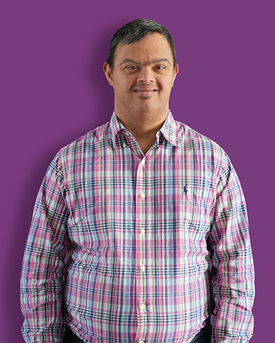 A portrait of our artist Sean against a purple background - Mawaheb Art Studio for People of Determination