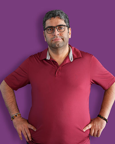 A portrait of our artist Zaid against a purple background - Mawaheb Art Studio for People of Determination